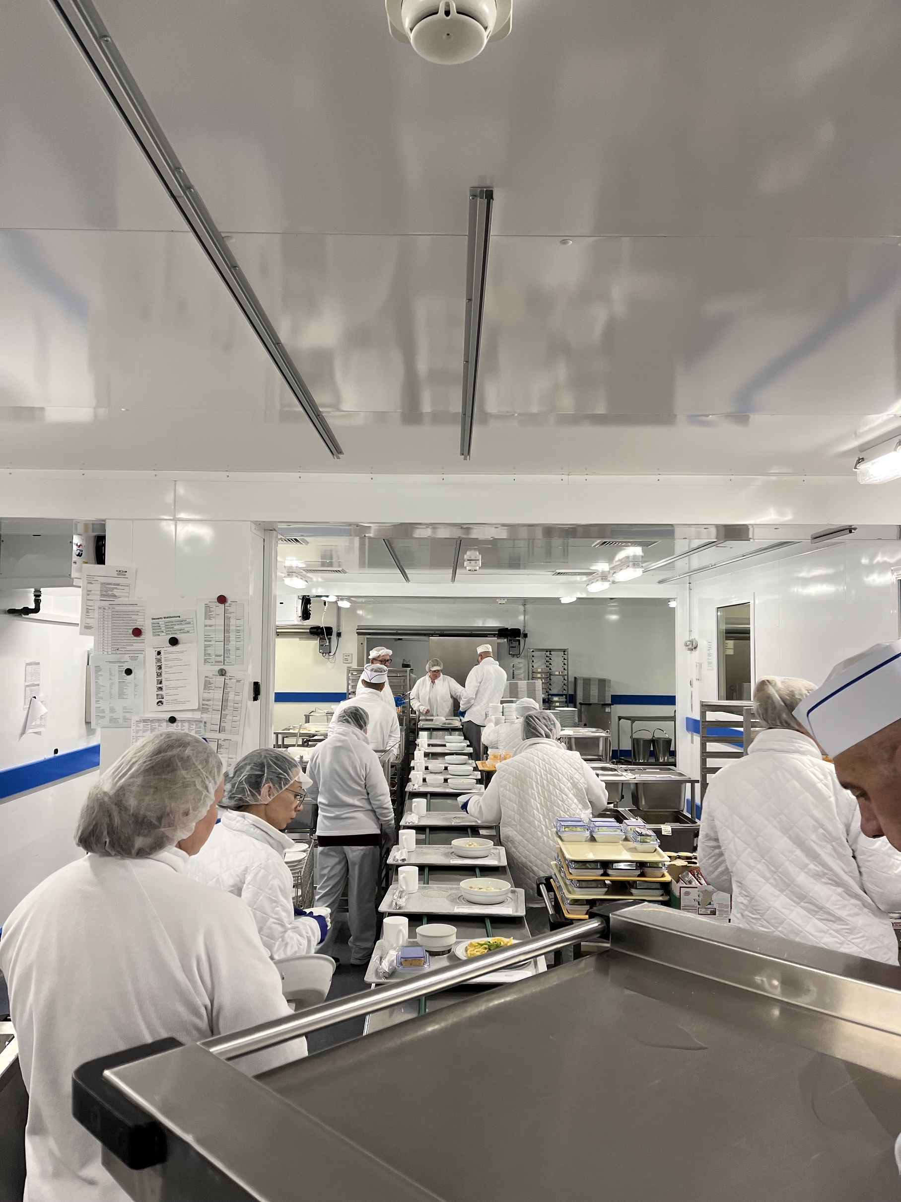 Die Mitarbeitenden der UKGM-Küche beladen die Tabletts entsprechend der Essenswünsche der Patient:innen. (Foto: Landkreis Gießen)