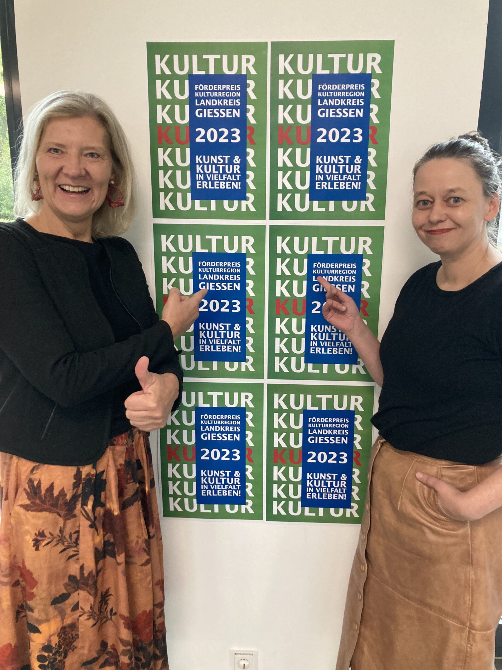 Landrätin Anita Schneider und Anja Horstmann vor dem Plakat zur Bewerbung des Förderpreises