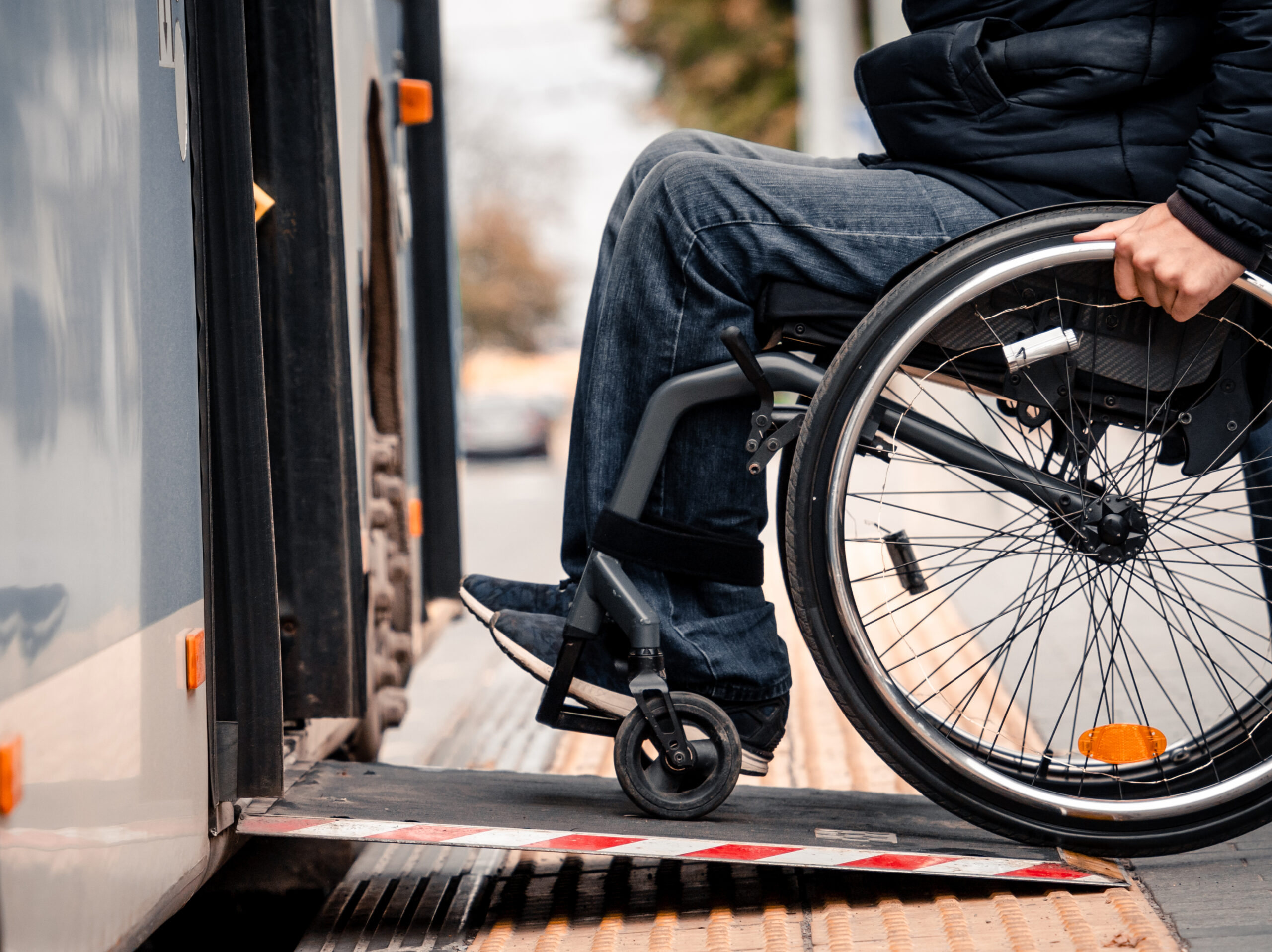 Mann im Rollstuhl fährt eine Rampe in einen Bus hoch
